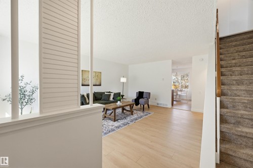 Open concept living area featuring light wood-finish flooring, white walls, and a textured ceiling - 8043 178 Street, Edmonton, AB - Indoor Photo Showing Other Room