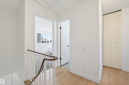 Upper-level landing featuring light wood-finish flooring, white walls, and a white baluster with a dark wood handrail - 8043 178 Street, Edmonton, AB - Indoor Photo Showing Other Room