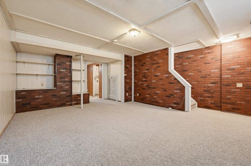 Spacious room featuring light-colored carpet flooring, exposed brick walls, built-in shelving, and recessed ceiling lights - 8043 178 Street, Edmonton, AB - Indoor Photo Showing Other Room