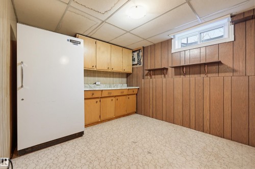 Kitchenette with wood paneling, light wood cabinetry, laminate countertops, and a white refrigerator - 8043 178 Street, Edmonton, AB - Indoor