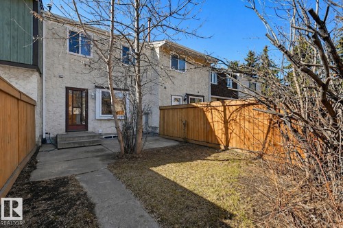 Rear exterior featuring stucco siding, multiple windows, a rear entry door, and concrete patio - 8043 178 Street, Edmonton, AB - Outdoor