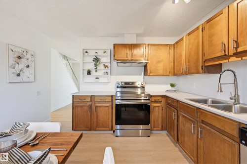 Kitchen featuring light wood cabinetry, stainless steel appliances, white countertops, and a dual basin sink with a modern gooseneck faucet - 8043 178 Street, Edmonton, AB - Indoor Photo Showing Kitchen With Double Sink