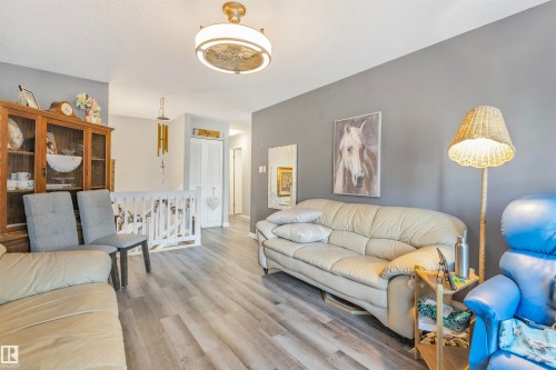 Living area featuring wood-finish flooring, a neutral color palette, and a white staircase railing - 1619 Knottwood Road N, Edmonton, AB - Indoor Photo Showing Living Room