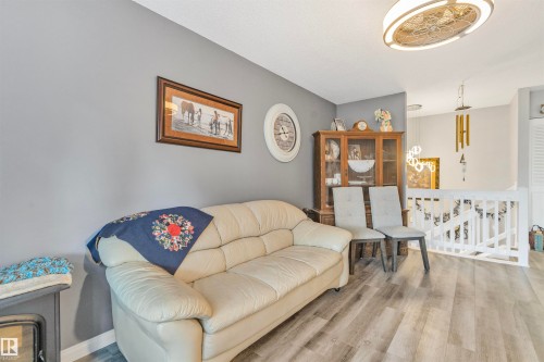 Spacious living area featuring light wood-finish flooring, a contemporary ceiling light fixture, and a white balustrade - 1619 Knottwood Road N, Edmonton, AB - Indoor Photo Showing Living Room
