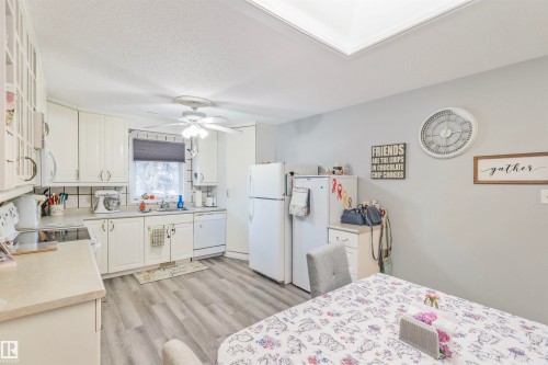 Kitchen featuring white cabinetry, light-toned countertops, tile backsplash, and wood-finish flooring - 1619 Knottwood Road N, Edmonton, AB - Indoor Photo Showing Kitchen With Double Sink