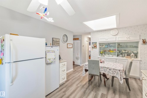 Kitchen area featuring wood-finish flooring, white cabinetry, and a built-in display hutch with glass doors - 1619 Knottwood Road N, Edmonton, AB - Indoor Photo Showing Dining Room