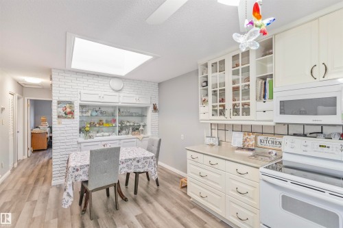 Kitchen space featuring wood-finish flooring and a white brick-patterned accent wall - 1619 Knottwood Road N, Edmonton, AB - Indoor