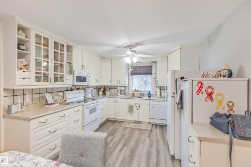 Kitchen featuring abundant white cabinetry, light-toned countertops, and wood-finish flooring - 1619 Knottwood Road N, Edmonton, AB - Indoor Photo Showing Kitchen