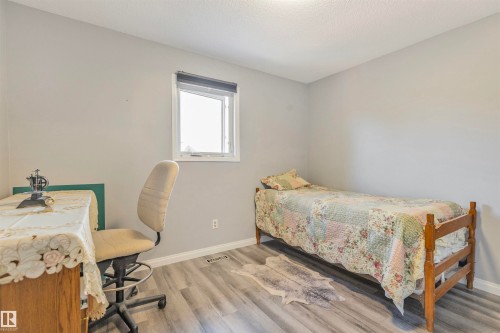Bedroom featuring wood-finish flooring, light gray wall paint, and a window with a roller shade - 1619 Knottwood Road N, Edmonton, AB - Indoor Photo Showing Bedroom