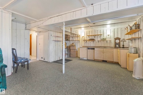 Spacious room with light gray carpeting, white vertical plank wall paneling, and exposed ceiling beams - 1619 Knottwood Road N, Edmonton, AB - Indoor Photo Showing Other Room