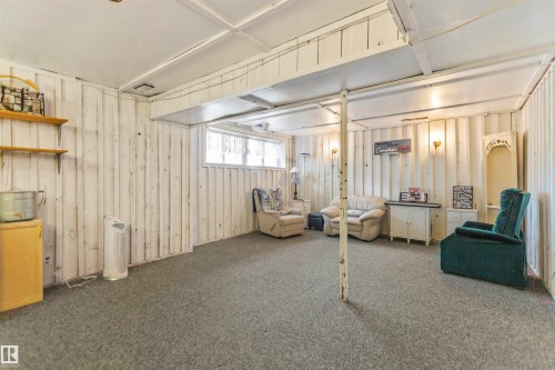 Spacious room featuring textured wall paneling, a neutral carpet, and a white ceiling with exposed beams - 1619 Knottwood Road N, Edmonton, AB - Indoor Photo Showing Basement