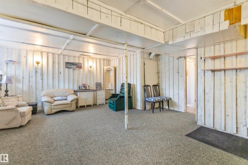 Spacious interior room with carpet flooring, white plank wall finishes, exposed beam ceiling, and wall sconce lighting - 1619 Knottwood Road N, Edmonton, AB - Indoor