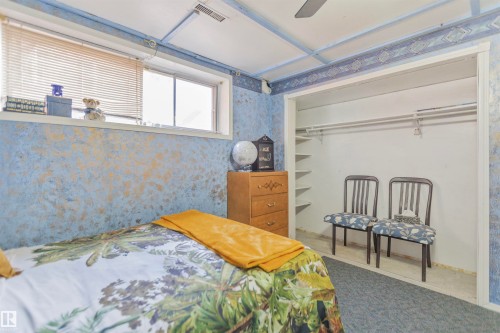 Bedroom featuring textured blue and gold walls, an overhead ceiling fan, and a built-in closet with shelving and hanging rods - 1619 Knottwood Road N, Edmonton, AB - Indoor Photo Showing Bedroom