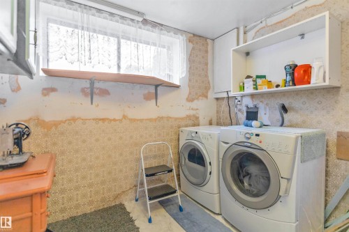 Dedicated laundry area featuring a washer and dryer, a window with natural light, a wood shelf, and an open wall-mounted storage unit - 1619 Knottwood Road N, Edmonton, AB - Indoor Photo Showing Laundry Room