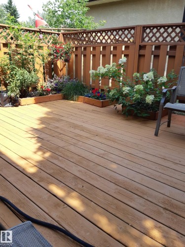 Spacious wood-plank deck featuring perimeter flower beds with mature plantings, and a privacy fence with lattice top detailing - 1619 Knottwood Road N, Edmonton, AB - Outdoor
