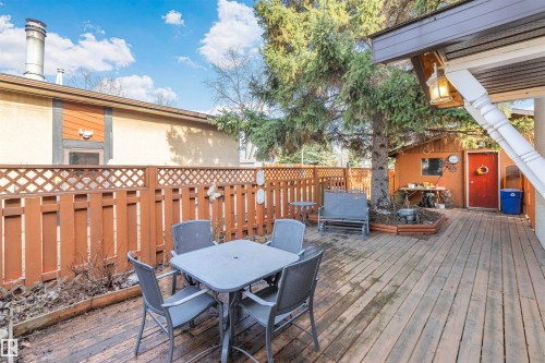 Expansive wood-finish deck featuring a privacy fence, mature trees, a detached storage shed, and an exterior wall lantern - 1619 Knottwood Road N, Edmonton, AB - Outdoor With Deck Patio Veranda With Exterior