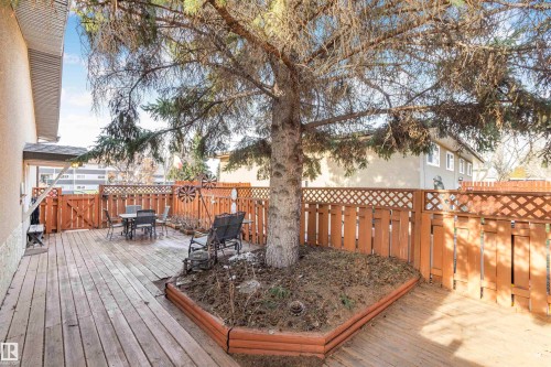 Expansive wood-finish deck featuring a built-in tree planter, full privacy fencing, and direct exterior access - 1619 Knottwood Road N, Edmonton, AB - Outdoor With Deck Patio Veranda