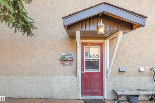 Entryway featuring a red paneled door with a glass insert, covered by a decorative overhang with an attached exterior light fixture - 1619 Knottwood Road N, Edmonton, AB - Outdoor