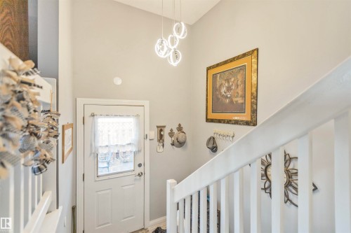 Entryway featuring a white paneled door with glass insert, light gray walls, a contemporary multi-ring chandelier, and white staircase railing - 1619 Knottwood Road N, Edmonton, AB - Indoor Photo Showing Other Room