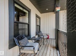 Inviting outdoor balcony featuring wood-finish flooring, vertical panel siding, and a contrasting dark trim - 