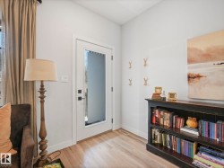 Entryway featuring a white door with frosted glass panel, light wood-finish flooring, white baseboards, and neutral wall tones - 