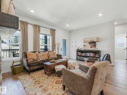Living area featuring recessed lighting, wood-finish flooring, a stone fireplace surround, and multiple windows - 