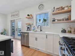 Kitchen featuring white cabinetry, light countertops, subway tile backsplash, stainless steel dishwasher, and wood-finish flooring - 
