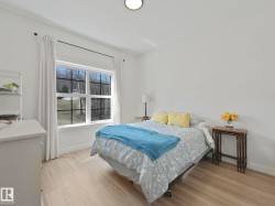 Bright interior space with light-tone wood-finish flooring, a large window featuring grid panes, and a flush-mount ceiling light fixture - 