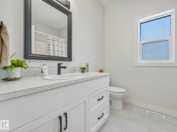 Bathroom featuring a white vanity with panel cabinetry and black hardware, a black-framed mirror, and a white sink with a matte black faucet - 