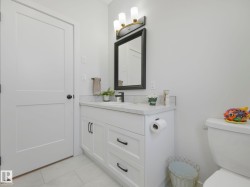 Bathroom featuring a white vanity with undermount sink, a light-colored countertop, and a black framed mirror - 