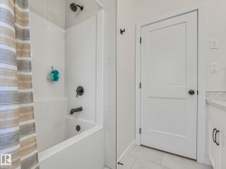 Tub and shower combination featuring matte black fixtures and a tiled surround - 