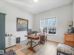 Room featuring light wood-finish flooring, white walls, and a large window with white trim overlooking a wooded area - 