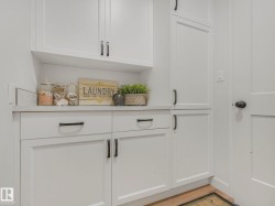 White shaker-style cabinetry with matte black hardware, light-toned countertop, and mosaic tile backsplash - 