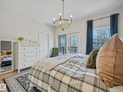 Bedroom featuring wood-finish flooring, a contemporary chandelier, and white walls - 