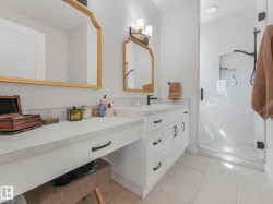 Contemporary bathroom featuring a spacious vanity with white cabinetry, a built-in dressing table, and a walk-in shower with a glass enclosure - 