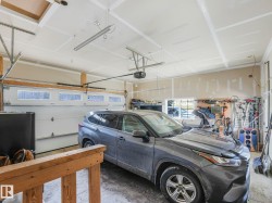 Attached garage with a white sectional door featuring transom windows, an automatic opener, and overhead fluorescent lighting - 