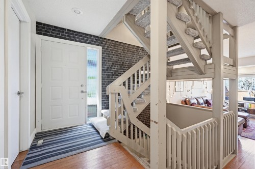 Entryway featuring light wood-finish flooring, a white paneled door with a sidelight, and a dark brick accent wall - 139 Wolf Willow Crescent, Edmonton, AB - Indoor Photo Showing Other Room