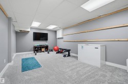 Finished basement space featuring light gray carpeting, gray painted walls, a drop ceiling with recessed lighting, and white baseboards - 