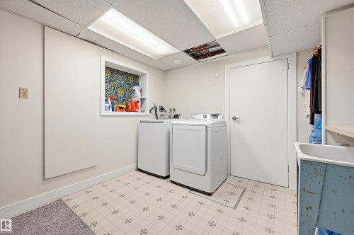 Dedicated utility space featuring patterned floor tile, recessed shelving with decorative backing, and a built-in wash basin - 139 Wolf Willow Crescent, Edmonton, AB - Indoor Photo Showing Laundry Room