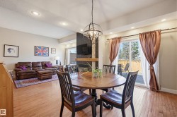 Open-concept dining area featuring wood-finish flooring, recessed lighting, and a contemporary spherical chandelier - 