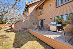Expansive wooden deck featuring exterior stairs, a sliding glass door, and a horizontal wood-paneled exterior - 