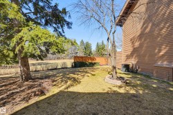 Spacious lawn area with mature trees, a wooden privacy fence, and a horizontal siding exterior - 