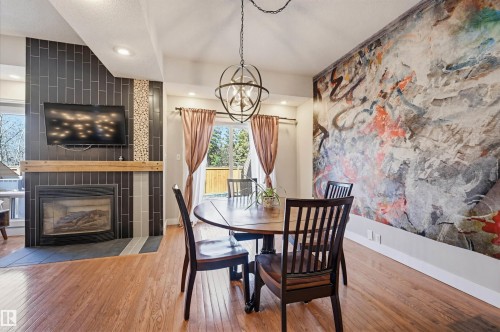 Spacious interior featuring wood-finish flooring and a contemporary fireplace with dark tile surround and a wood mantel - 139 Wolf Willow Crescent, Edmonton, AB - Indoor Photo Showing Dining Room With Fireplace