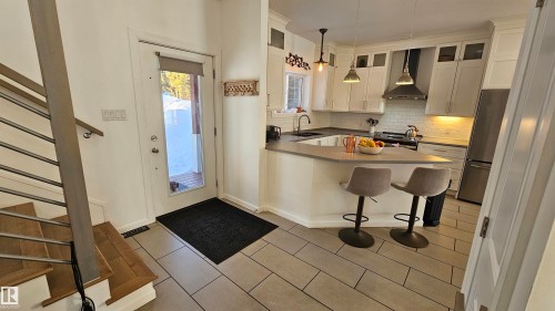 Kitchen featuring stainless steel appliances, tasteful backsplash, pendant lighting, a breakfast bar, and a peninsula - 58513 Range Road 231, Rural Thorhild County, AB - Indoor Photo Showing Kitchen With Double Sink
