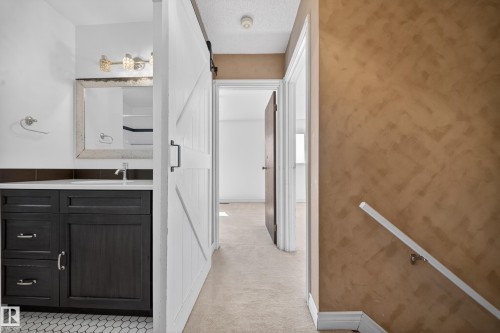 Bathroom vanity with dark wood-finish cabinetry, white countertop, and hexagonal tile flooring - 1767 61 Street, Edmonton, AB - Indoor