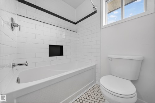 White subway tile tub surround with an integrated black accent niche, chrome fixtures, and a white bathtub - 1767 61 Street, Edmonton, AB - Indoor Photo Showing Bathroom