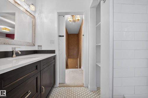 Bathroom vanity featuring a dark wood-finish cabinet, white countertop, and brushed nickel faucet - 1767 61 Street, Edmonton, AB - Indoor Photo Showing Bathroom