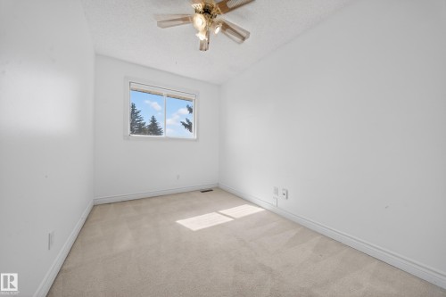 Carpeted room featuring a ceiling fan with integrated lighting, a window with exterior views, white walls, and white baseboards - 1767 61 Street, Edmonton, AB - Indoor Photo Showing Other Room
