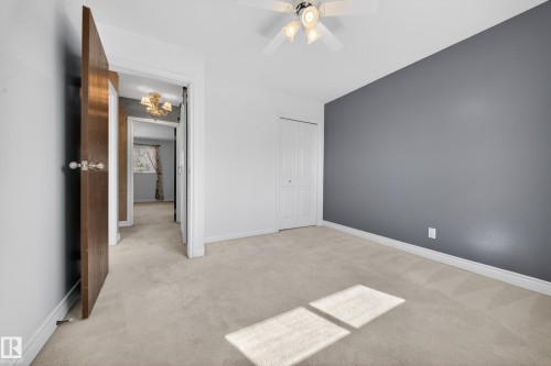 Bedroom featuring soft carpeting, a bi-fold closet, a ceiling fan with integrated lighting, and a contrasting accent wall - 1767 61 Street, Edmonton, AB - Indoor Photo Showing Other Room