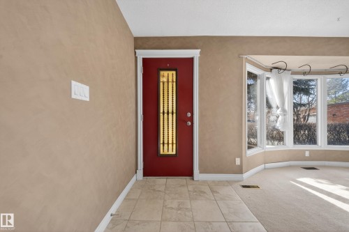 Entryway featuring a red door with decorative glass inserts, tile flooring, and a bay window - 1767 61 Street, Edmonton, AB - Indoor Photo Showing Other Room